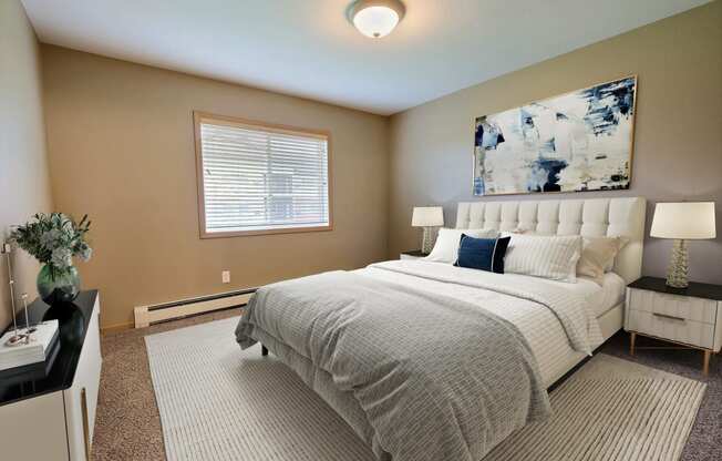 a bedroom with a bed and a painting on the wall. Fargo, ND Urban Plains Apartments