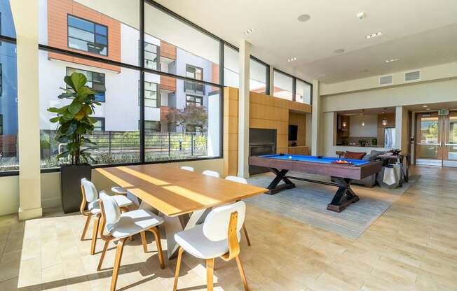 A room with a long table and chairs and a pool table.
