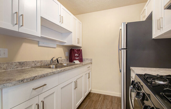 a kitchen with white cabinets and a stainless steel refrigerator at Old Farm Apartments, Elkhart, Indiana