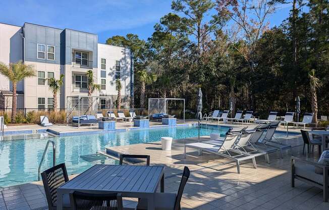 A pool area with chairs and a table in front of a building.