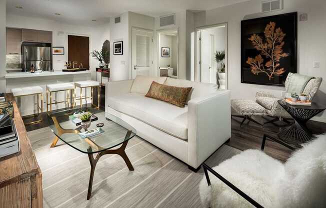 A modern living room with a white couch and a glass coffee table.
