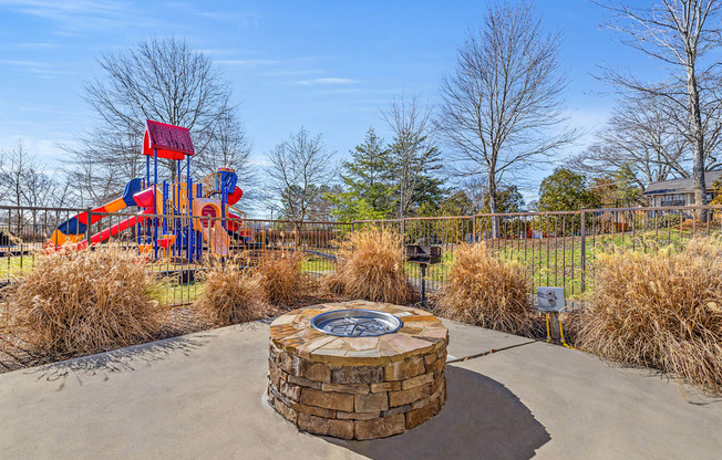 A playground with a red and blue slide and a circular stone structure in the middle.