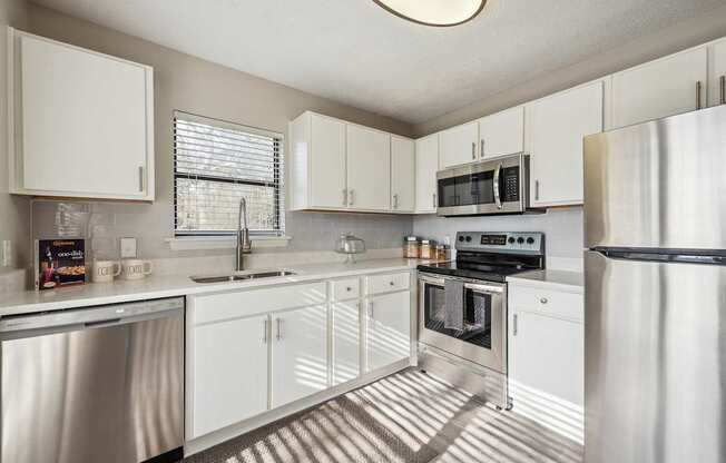 A modern kitchen with white cabinets and stainless steel appliances.