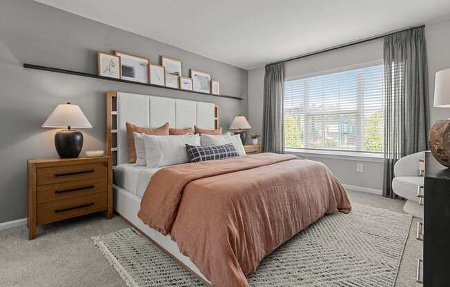 A bedroom with a large bed and a window with curtains.