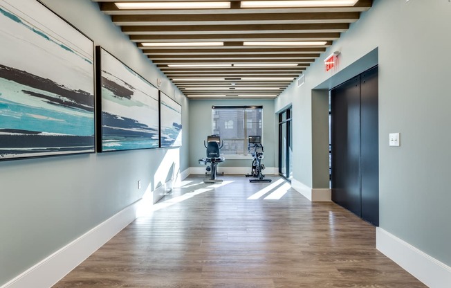 a hallway with a chair and paintings on the wall and a door