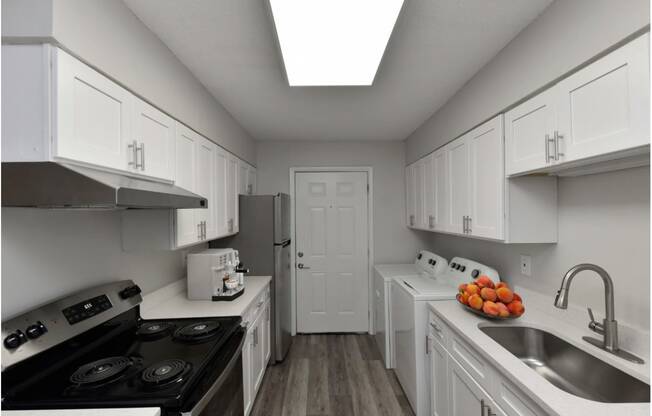 a kitchen with white cabinets and appliances and a sink