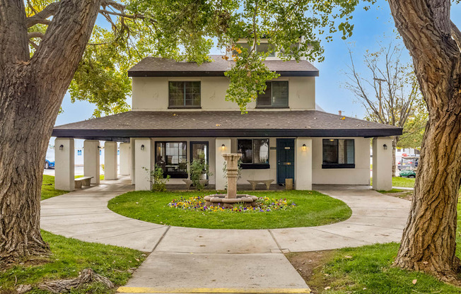 a house with a fountain in the center of a circle of grass