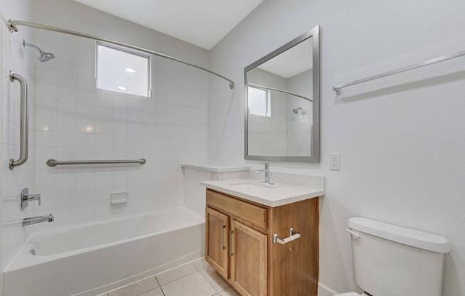 A white bathroom with a wooden cabinet and a white toilet.