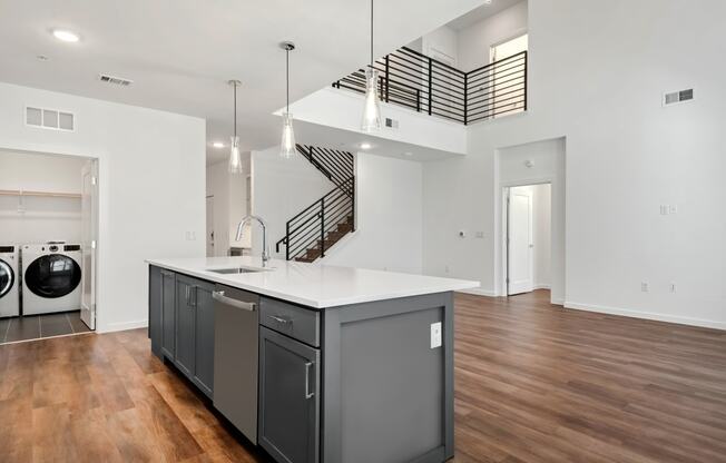a kitchen with an island and a laundry room with a staircase