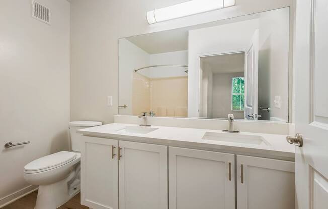 A white bathroom with a toilet, sink, and mirror.