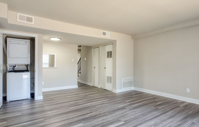 an empty living room with a refrigerator and a washer and dryer