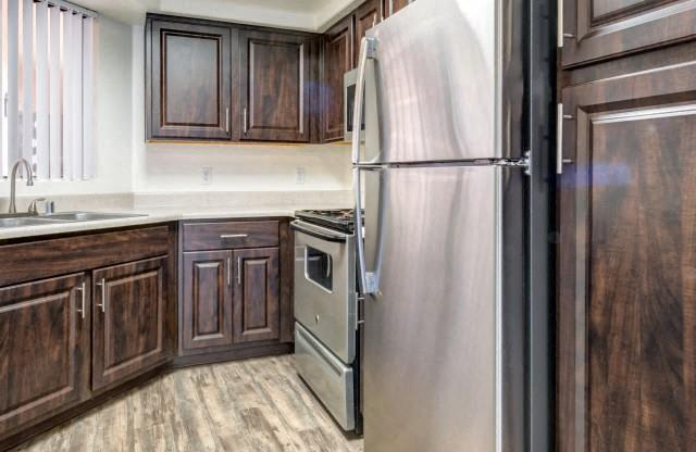 Ingleside Apartments kitchen with light brown floors, dark brown cabinets and stainless steel appliances