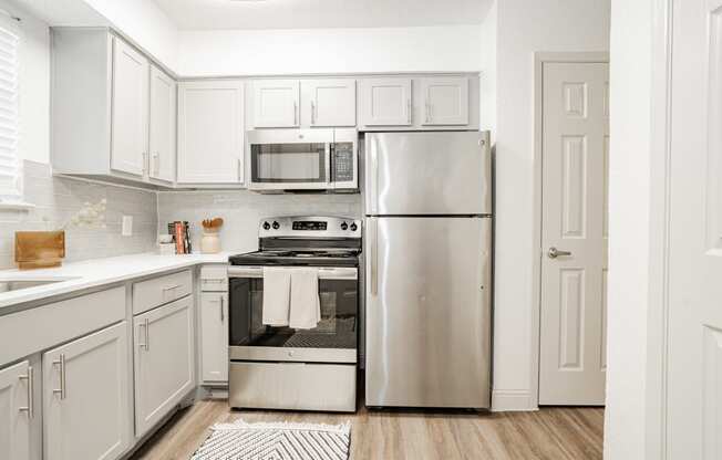 a white kitchen with stainless steel appliances and white cabinets