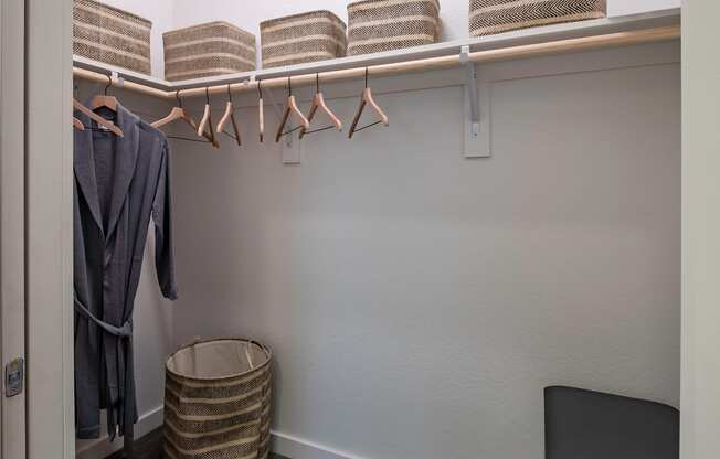 A laundry room with a washer and dryer, a basket, and clothes hanging up.