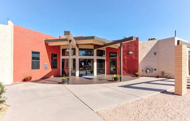 A building with a red and beige exterior has a covered walkway leading to the entrance.