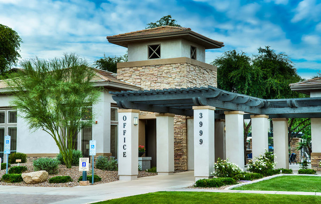 A building with the word "OFFICE" on it is surrounded by greenery.