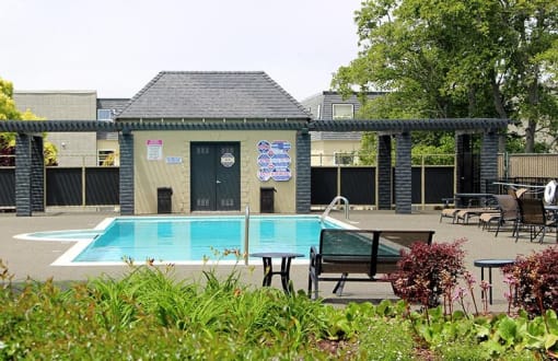 a swimming pool in front of a building with a bench