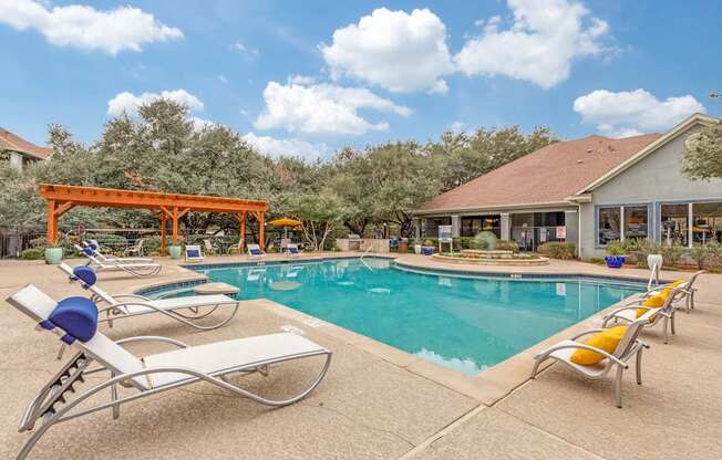 A pool with sun loungers and a building in the background.