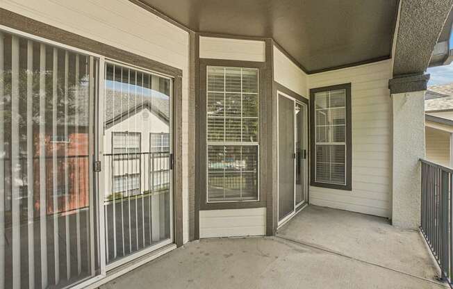 A patio with a sliding glass door and a metal railing.