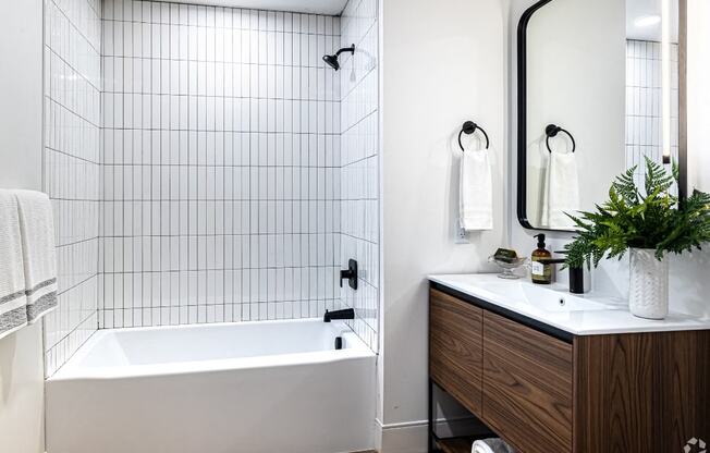 a white bathroom with a tub and a sink and a mirror