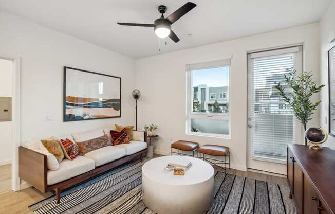 a living room with a couch and a coffee table and a ceiling fan