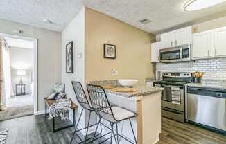 a kitchen with a bar and three stools in front of a counter top