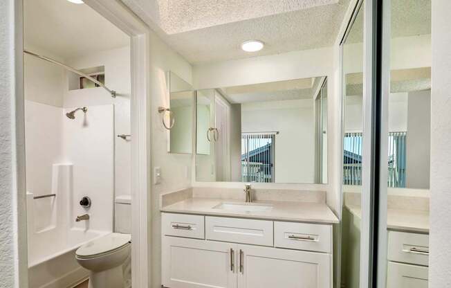 A white bathroom with a shower, sink, and mirror.