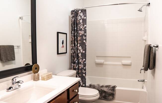 a bathroom with white fixtures and a black and white shower curtain