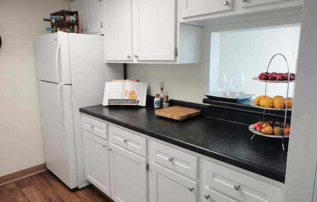 a kitchen with white cabinets and a black counter top