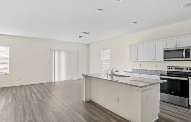 a kitchen and living room with wood floor and white walls