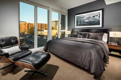 A bedroom with a large bed, a chair, and a painting on the wall.