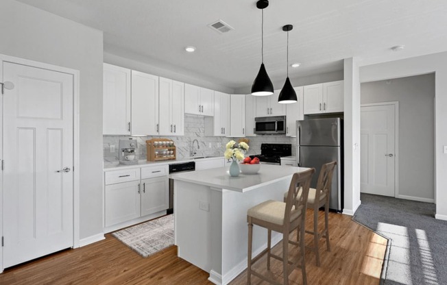 a kitchen with white cabinets and a white island with chairs