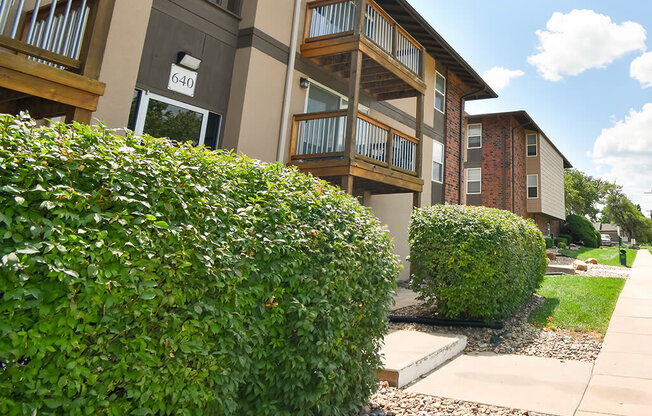 a building with a sidewalk and hedges in front of it