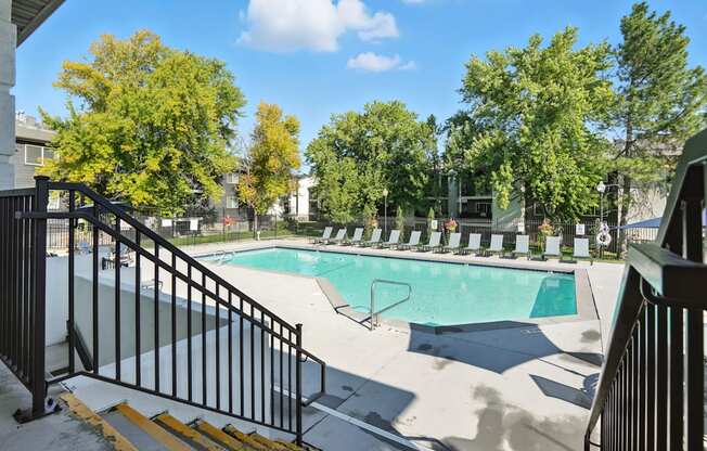 A pool surrounded by trees and a black fence.