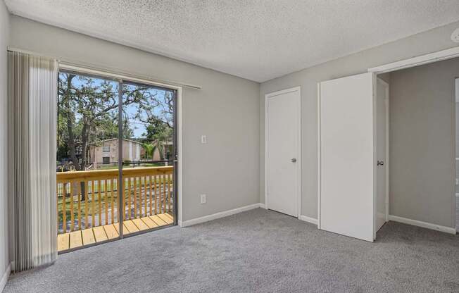 A room with a sliding glass door leading to a balcony.