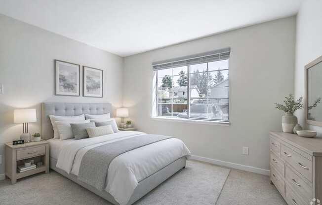 A bedroom with a large bed, nightstands, and a window overlooking a residential area.