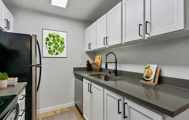 A kitchen with a black refrigerator and white cabinets.