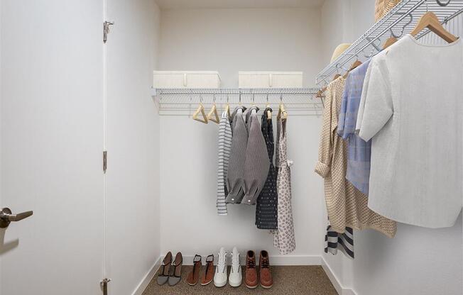 a walk in closet with a rack of clothes and shoes