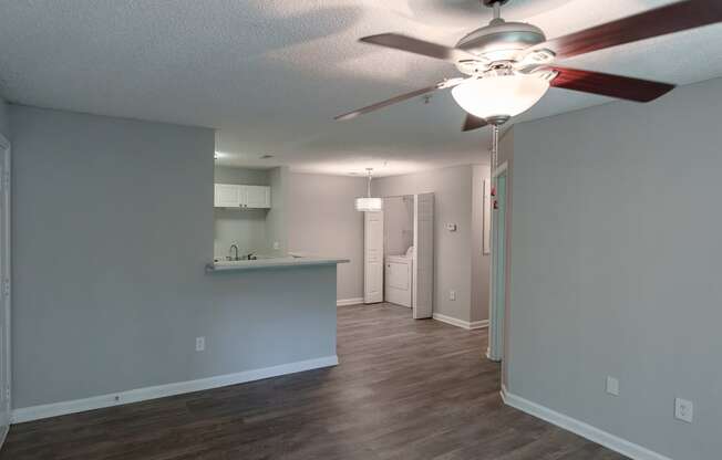 an empty living room and kitchen with a ceiling fan