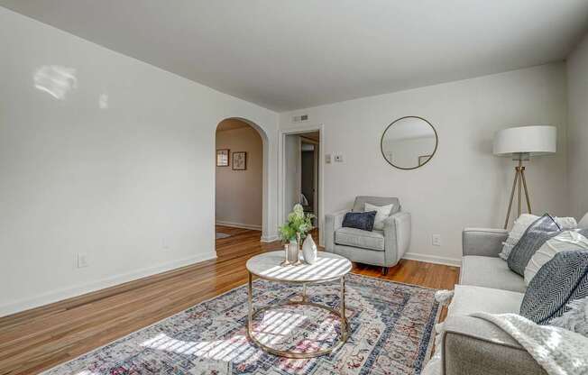 A living room with a round table and a grey couch.