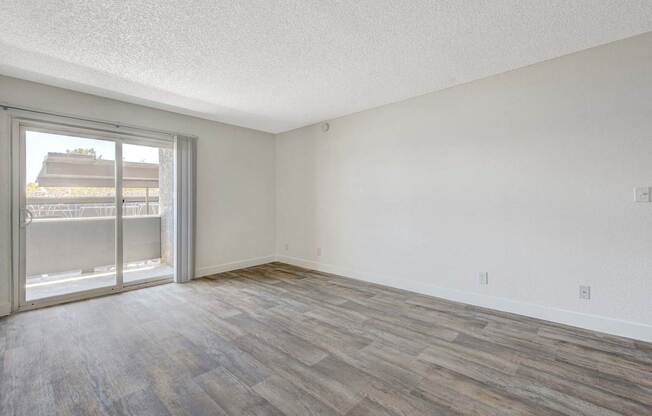 A room with a sliding glass door and wood flooring.