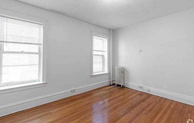 A room with wooden floors and two windows.