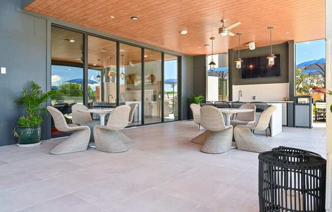 a covered patio with wicker chairs and a flat screen tv