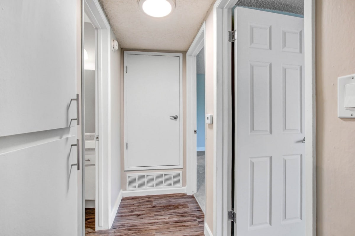 an empty hallway with a white door and a door to a closet