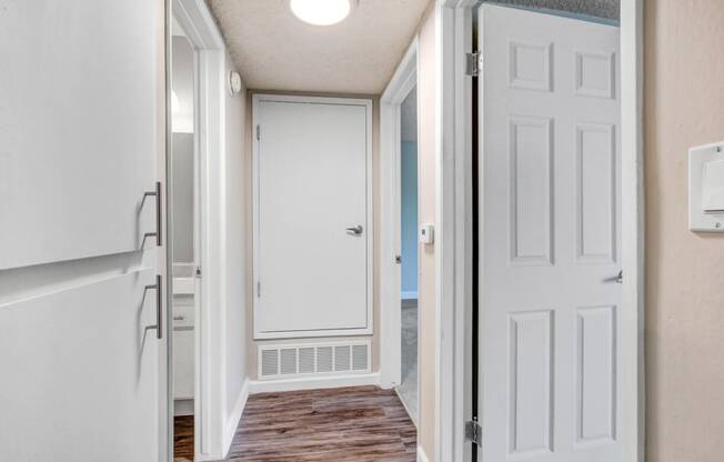 an empty hallway with a white door and a door to a closet