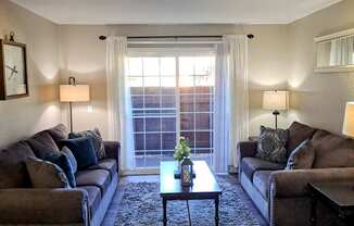 A living room with two couches, a coffee table, and a window.