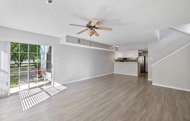 A spacious room with a ceiling fan and light wood flooring.