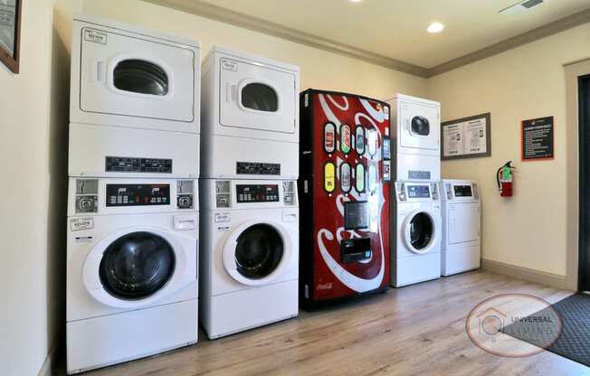 a laundry room with a row of washing machines and a coca cola refrigerator