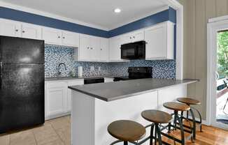 a kitchen with a large island with four stools in front of it