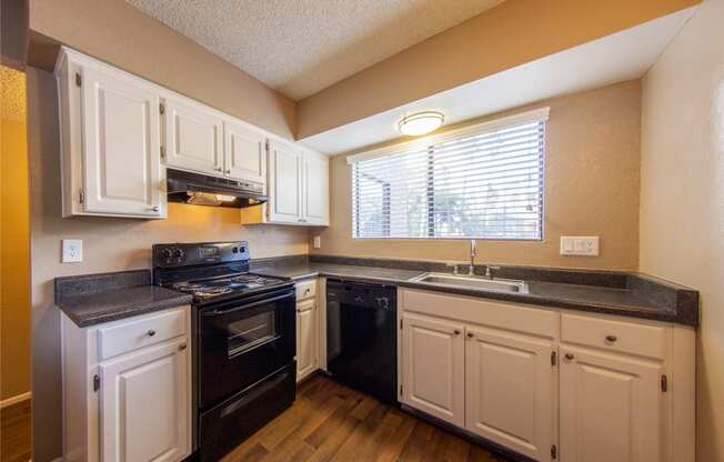 a kitchen with white cabinets and black appliances and a window